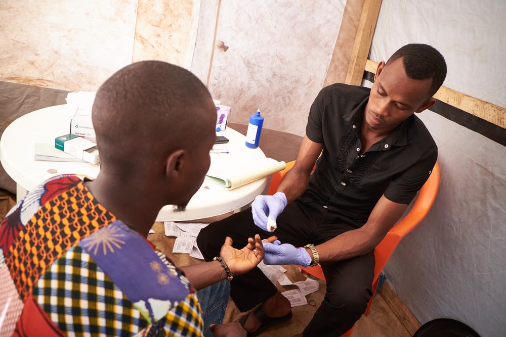 Mohamed (left) is tested for HIV by activist Mamadou at the Médecins Sans Frontiers (MSF) mobile clinic in the neighbourhood of Sangoyah Market, Conakry, Guinea on March 17, 2016.
